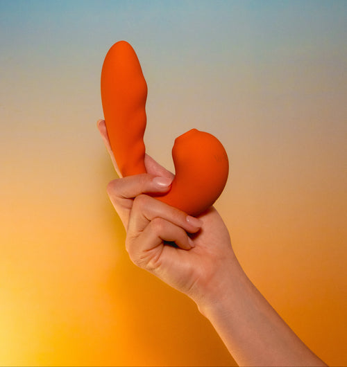 Labas Aurea orange pleasure massager held in hand to show its compact, portable size and soft-touch silicone texture, designed for gentle suction and vibration for external stimulation and light vaginal insertion.