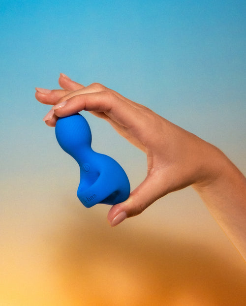 Labas Loopé blue finger vibrator held by a hand model to demonstrate its flexible, wearable design and compact size for targeted external stimulation.