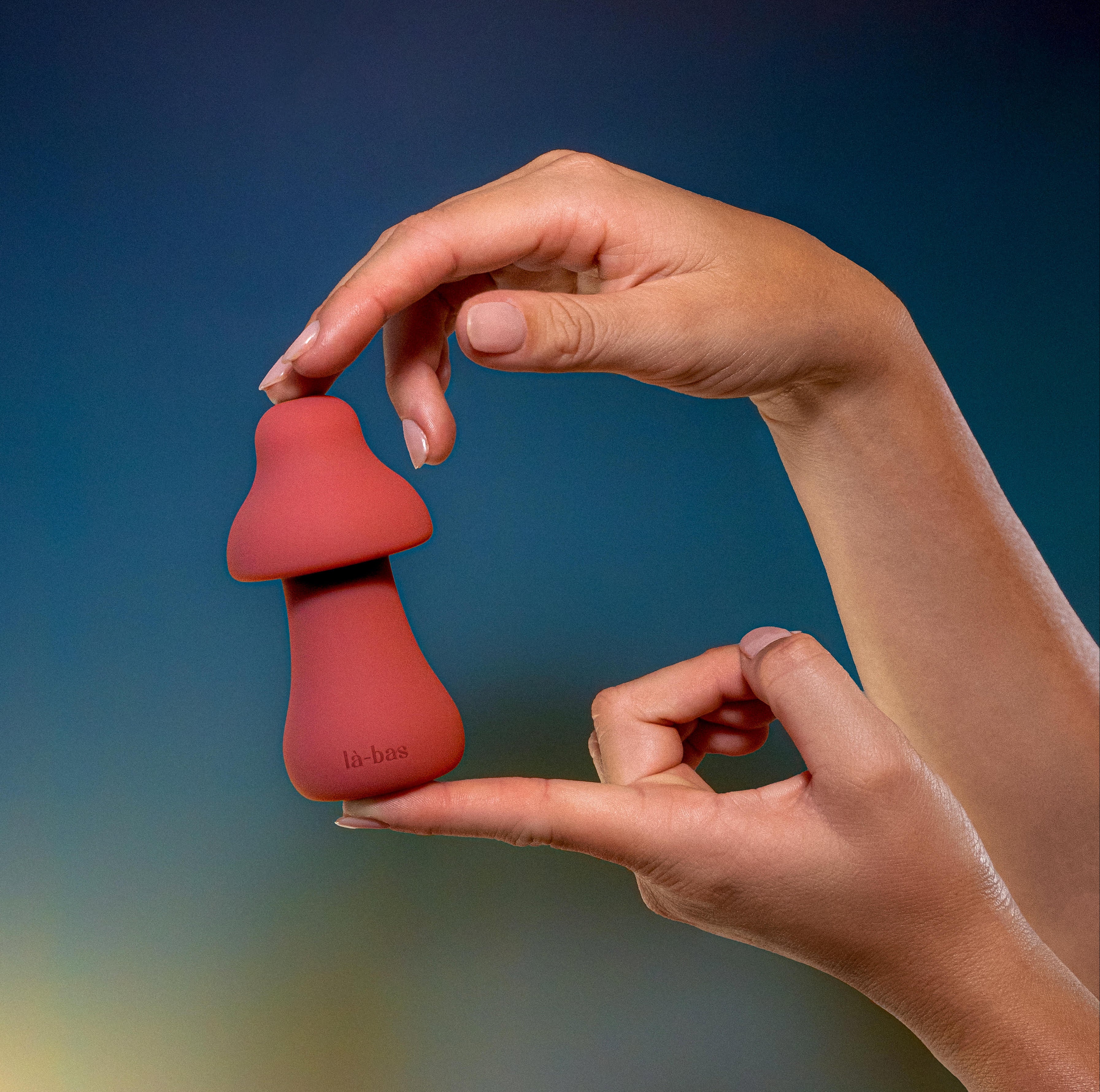 Labas Mushy rose gold pleasure massager held in hand to demonstrate its compact, portable size and soft-touch silicone texture for external stimulation.