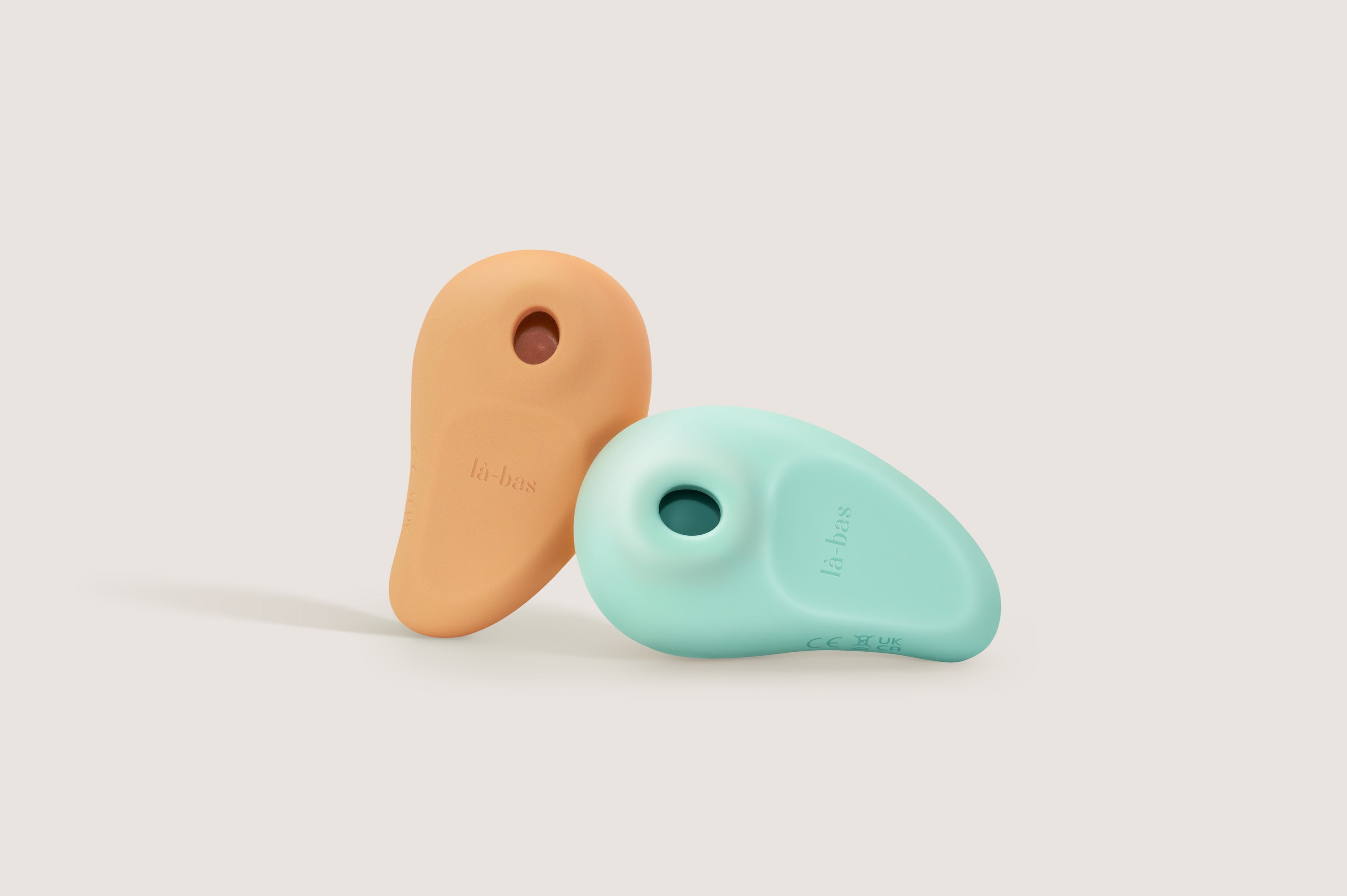 La-bas Orae suction vibrators in mint green and orange, a duo of tropical-inspired pleasure tools.